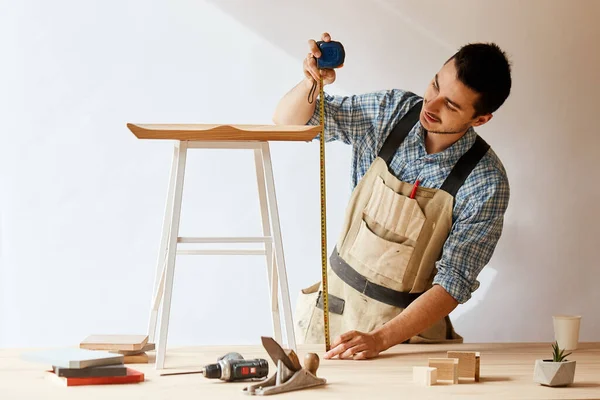 Молодий чоловік вимірює домашні меблі з мірною стрічкою. Концепція ремонту . — стокове фото