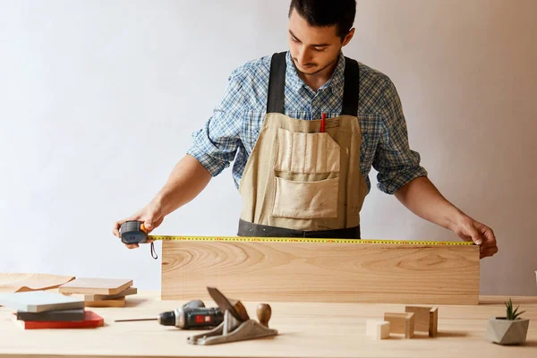 Молодий чоловік вимірює домашні меблі з мірною стрічкою. Концепція ремонту . — стокове фото