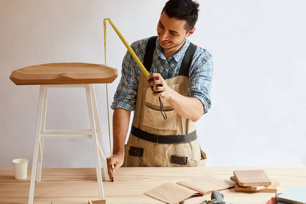 Mano de un carpintero que mide una tabla de madera — Foto de Stock