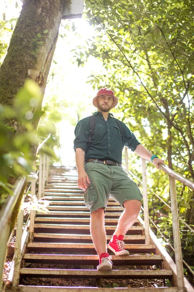 Voyageur avec sac à dos escalade sur pont en bois dans la forêt verte — Photo