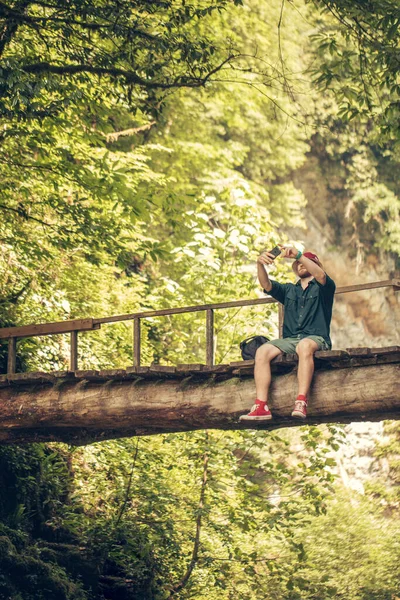 Traveler crosses through hanging bridge in the green summer forest. — Stock Photo, Image
