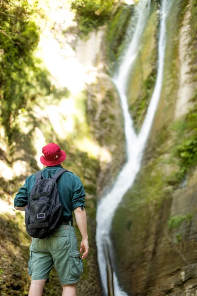 Colpo posteriore del viaggiatore maschile con le mani sollevate prima della cascata in Islanda — Foto Stock