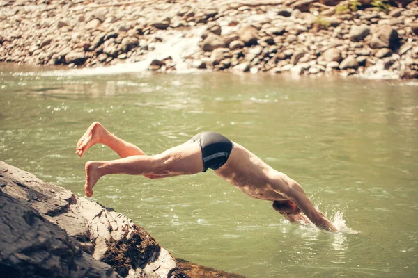 Jovem saltando para a água da margem do lago. Tourist Relax conceito. — Fotografia de Stock