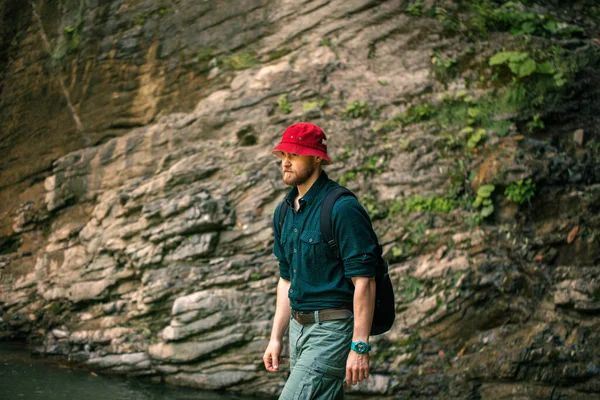 Hiker with backpack walking in mountain forest, climbing to the cliff — Stock Photo, Image