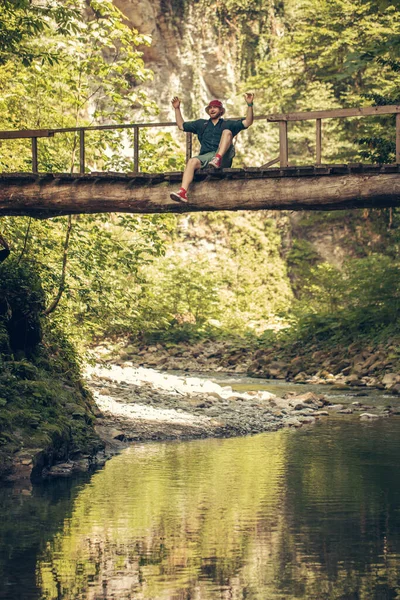 Voyageur traverse un pont suspendu dans la forêt verte d'été. — Photo