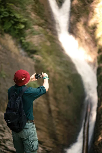 Hiker tiene smartphone cercando di trovare la connessione nella foresta profonda con cascate. — Foto Stock