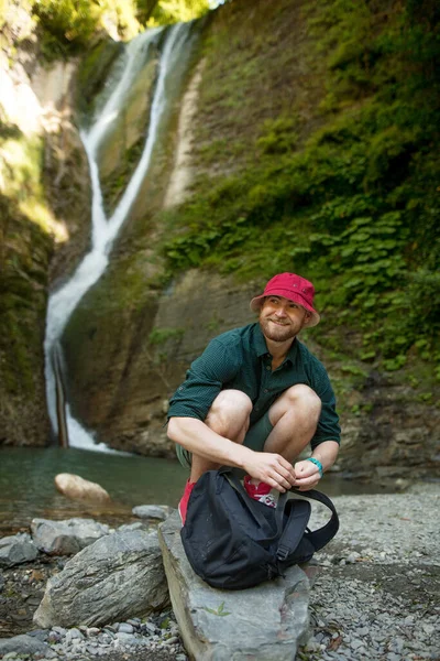 Jovem acampamento turístico com mochila perto de uma cachoeira na floresta. — Fotografia de Stock