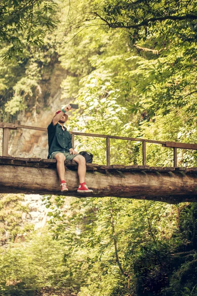 Мандрівник перетинає висячий міст у зеленому літньому лісі . — стокове фото