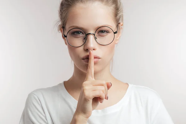 Mujer joven caucásica sosteniendo su dedo a sus labios llamando para guardar silencio. —  Fotos de Stock