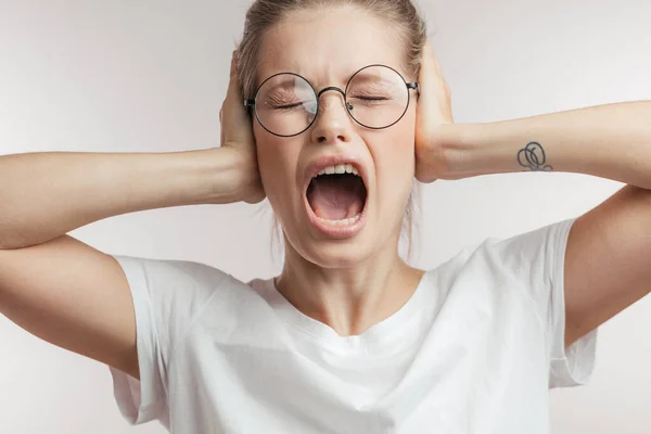 Mujer caucásica indignada cubriendo las orejas con las manos y gritando, tiro aislado. —  Fotos de Stock