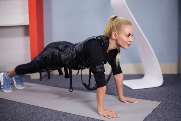 Ehrfürchtiges Mädchen macht Liegestütze, während es mit dem EMS-Gerät verbunden ist — Stockfoto