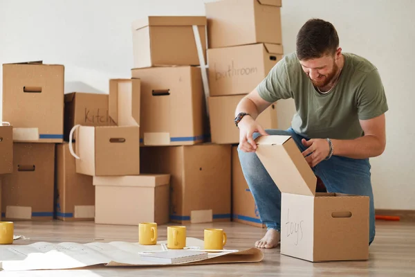 Hombre en nuevo apartamento desembalaje cajas de cartón —  Fotos de Stock