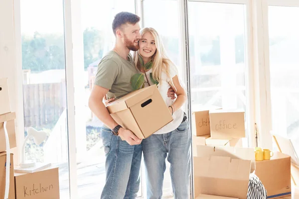 Pareja feliz llevando cajas de cartón en un nuevo hogar en el día de mudanza — Foto de Stock