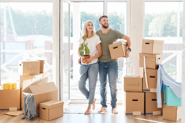 Pareja feliz llevando cajas de cartón en un nuevo hogar en el día de mudanza — Foto de Stock