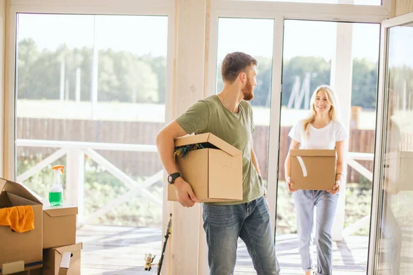 Pareja feliz llevando cajas de cartón en un nuevo hogar en el día de mudanza — Foto de Stock