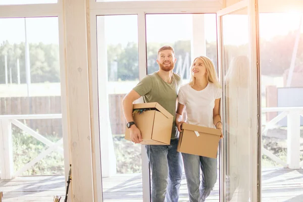 Pareja feliz llevando cajas de cartón en un nuevo hogar en el día de mudanza — Foto de Stock