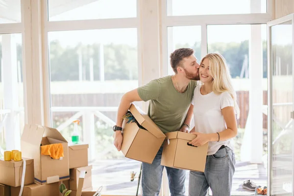 Pareja feliz llevando cajas de cartón en un nuevo hogar en el día de mudanza — Foto de Stock