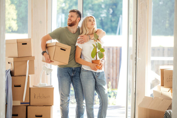 Счастливая пара носит картонные коробки в новый дом в день переезда