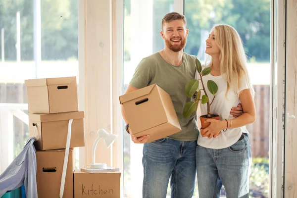 Счастливая пара носит картонные коробки в новый дом в день переезда — стоковое фото
