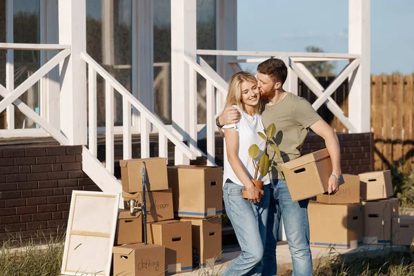 Esposo y esposa de pie frente a la nueva casa de compra con cajas — Foto de Stock