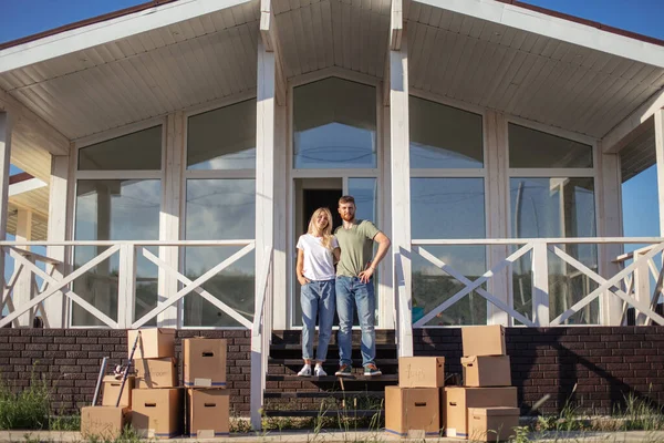สามีและภรรยายืนอยู่หน้าบ้านซื้อใหม่พร้อมกล่อง — ภาพถ่ายสต็อก
