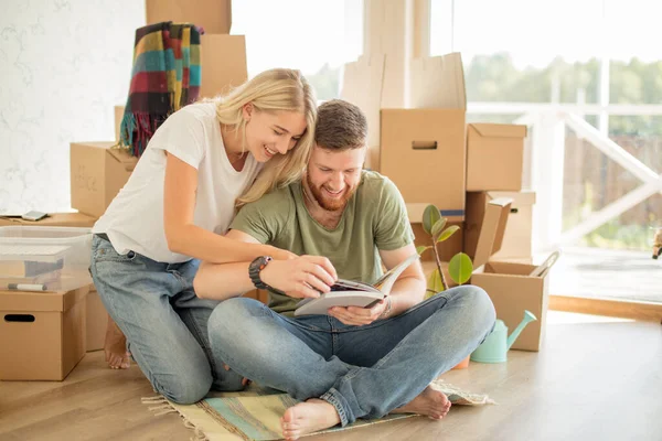 Pareja con libro sentado en la cama mientras se muda a un nuevo hogar — Foto de Stock