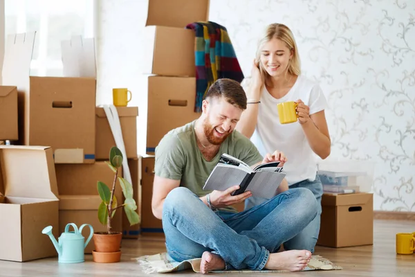 Coppia con libro seduto sul letto mentre si trasferisce in una nuova casa — Foto Stock