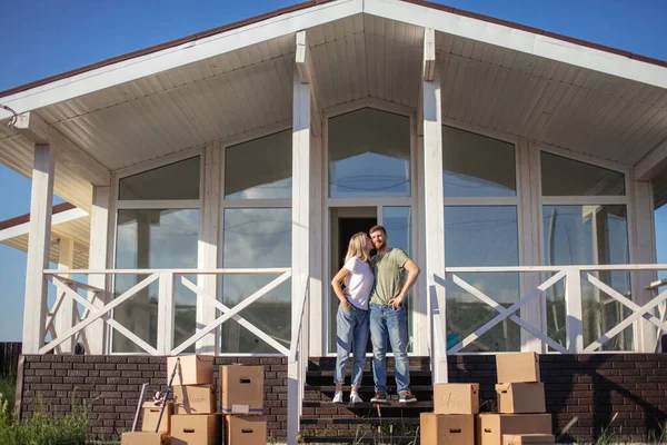 Esposo y esposa de pie frente a la nueva casa de compra con cajas —  Fotos de Stock