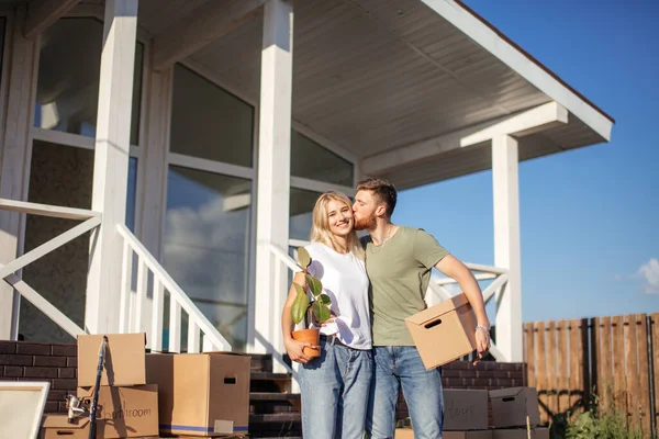 Чоловік і дружина стоять перед новою покупкою будинку з коробками — стокове фото