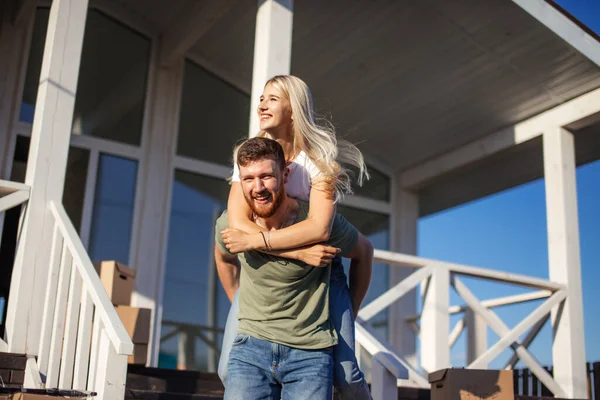 Couple enjoying near new apartment and husband piggyback wife outside — Stock Photo, Image