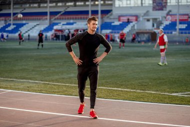 Siyah spor giyimli erkek sporcu pistte koşuyor.