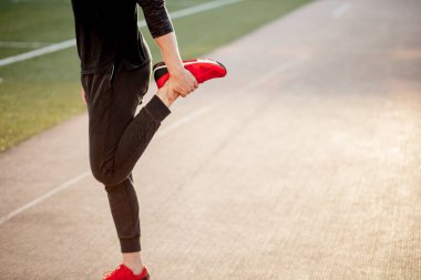 Adam stadyumdaki yarış pistinde koşmadan önce vücudu gerer.