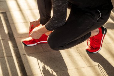 Koşucu hazırlanıyor koşu ayakkabılarını bağlarken raylarda oturuyor.