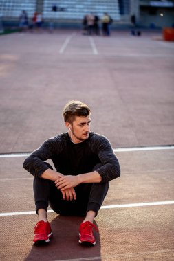 Dinlenme zamanı. Stadyumda koşan bir adam dinleniyor.