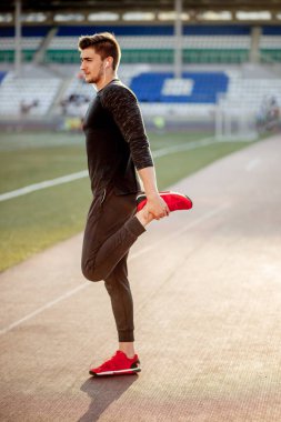 Adam stadyumdaki yarış pistinde koşmadan önce vücudu gerer.