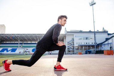 Adam stadyumdaki yarış pistinde koşmadan önce vücudu gerer.