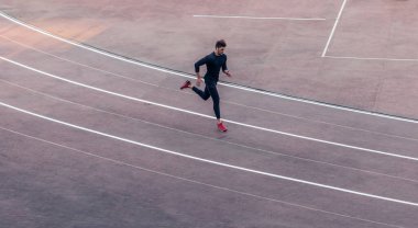 Top view Sporcusu koşu pistinde koşuyor. Koşucu stadyumdaki kırmızı pistte koşuyor.