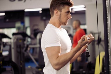 Vücut geliştirici beden eğitimi öğretmeniyle egzersiz yapıyor.