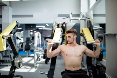 Genç bir atlet spor salonunda antrenman yapıyor. Vücut geliştirici üst vücut kaslarını şişiriyor.