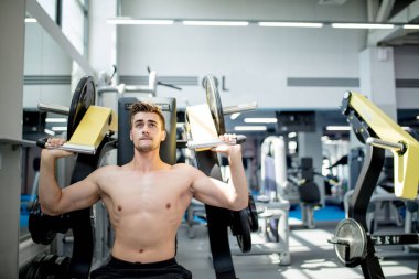 Genç bir atlet spor salonunda antrenman yapıyor. Vücut geliştirici üst vücut kaslarını şişiriyor.