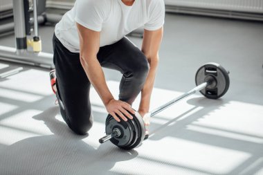 Kas yığını olan adam spor salonunda ağırlık kaldırıyor.