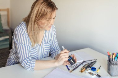 Kadınlar yazı yazarlar, işaret fırçası kullanarak kağıt üzerinde sanat yaparlar.