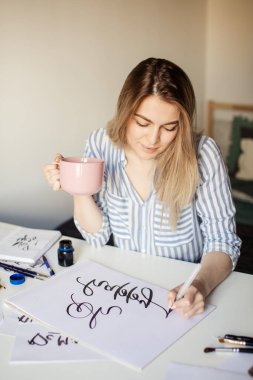 Kahve ya da çay içerken beyaz masaya güzel notlar yazan kadını kapat.