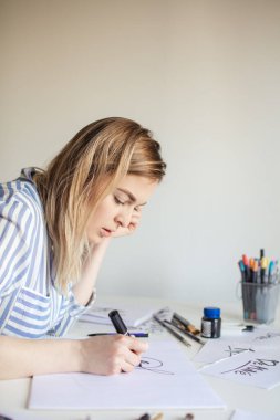 Kadınlar yazı yazarlar, işaret fırçası kullanarak kağıt üzerinde sanat yaparlar.