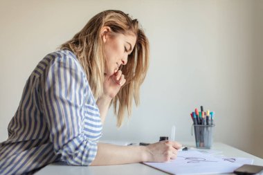 Kadınlar yazı yazarlar, işaret fırçası kullanarak kağıt üzerinde sanat yaparlar.