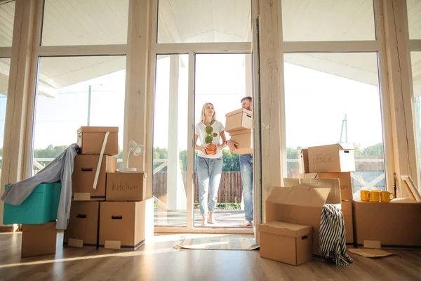 Pareja feliz llevando cajas de cartón en un nuevo hogar en el día de mudanza — Foto de Stock