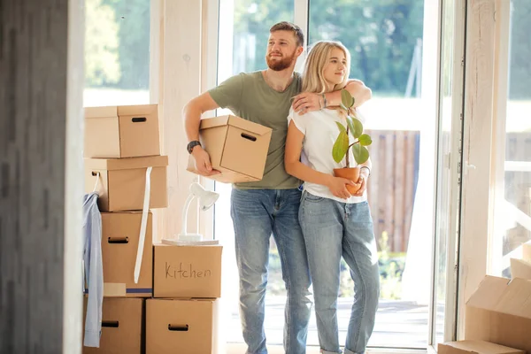 Pareja feliz llevando cajas de cartón en un nuevo hogar en el día de mudanza — Foto de Stock