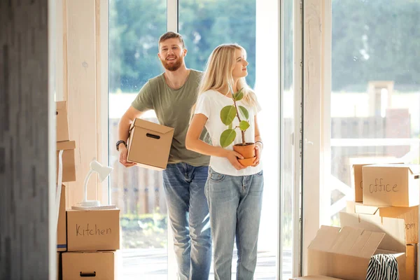 Pareja feliz llevando cajas de cartón en un nuevo hogar en el día de mudanza — Foto de Stock