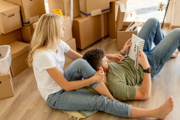 couple with book sitting on bed while moving into new home