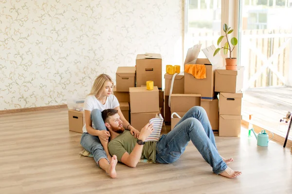 Couple with book sitting on bed while moving into new home — Stock Photo, Image